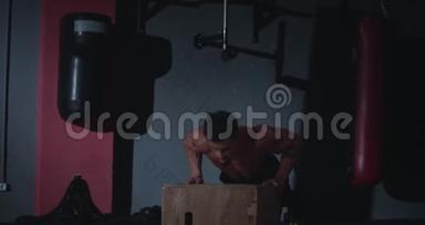 在交叉健身课上，一个<strong>身材完美</strong>的年轻人在木箱上做俯卧撑，他得到了甜蜜